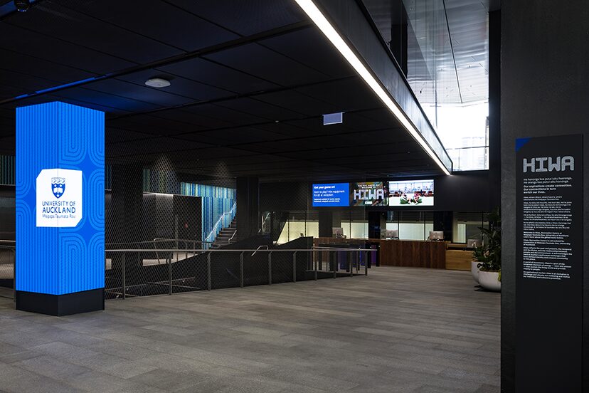 Blue University of Auckland branding on a digital column in the Hiwa lobby.