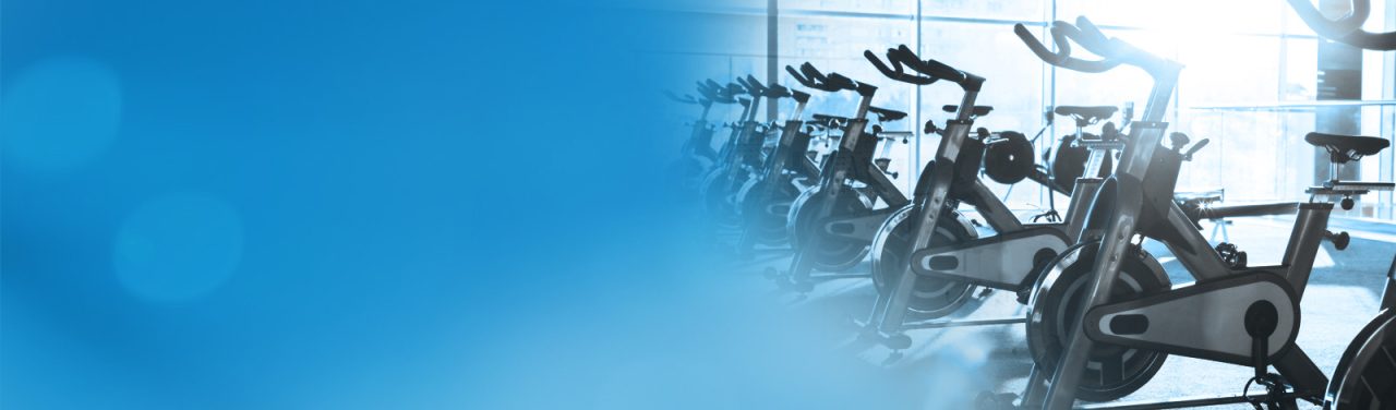 Exercise bikes fading into a blue banner background.